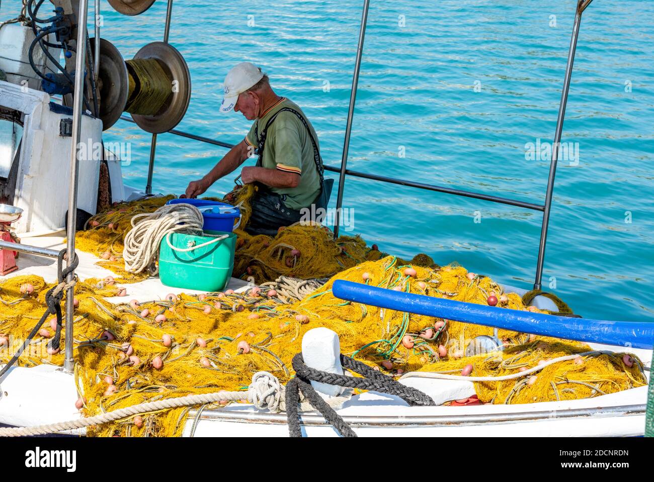 a traditional greek fisherman mending his nets in the harbour at zante town, zakynthos, greece Stock Photo
