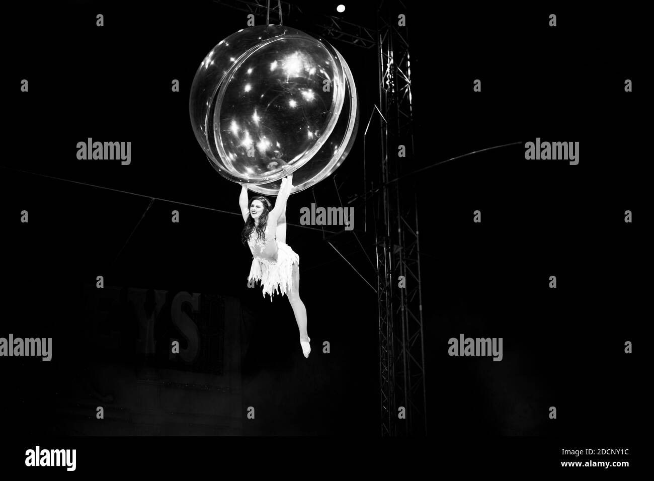 Acrobatic, circus performer, girl in a bubble, gymnast, aerial performance, doing the splits, hanging, dare-devil, dangerous performance Stock Photo