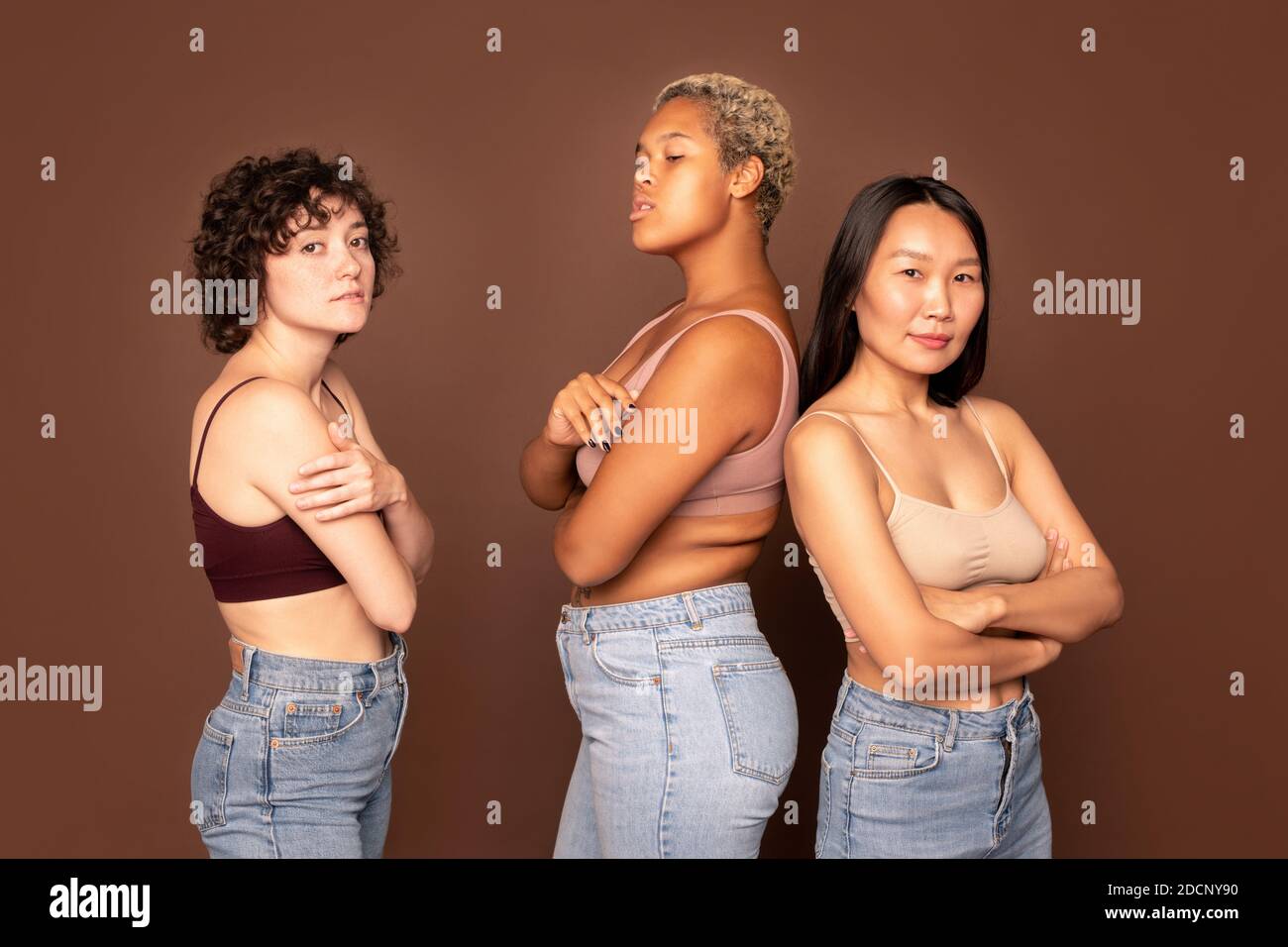 Group of young beautiful females in tanktops and blue jeans standing in row Stock Photo