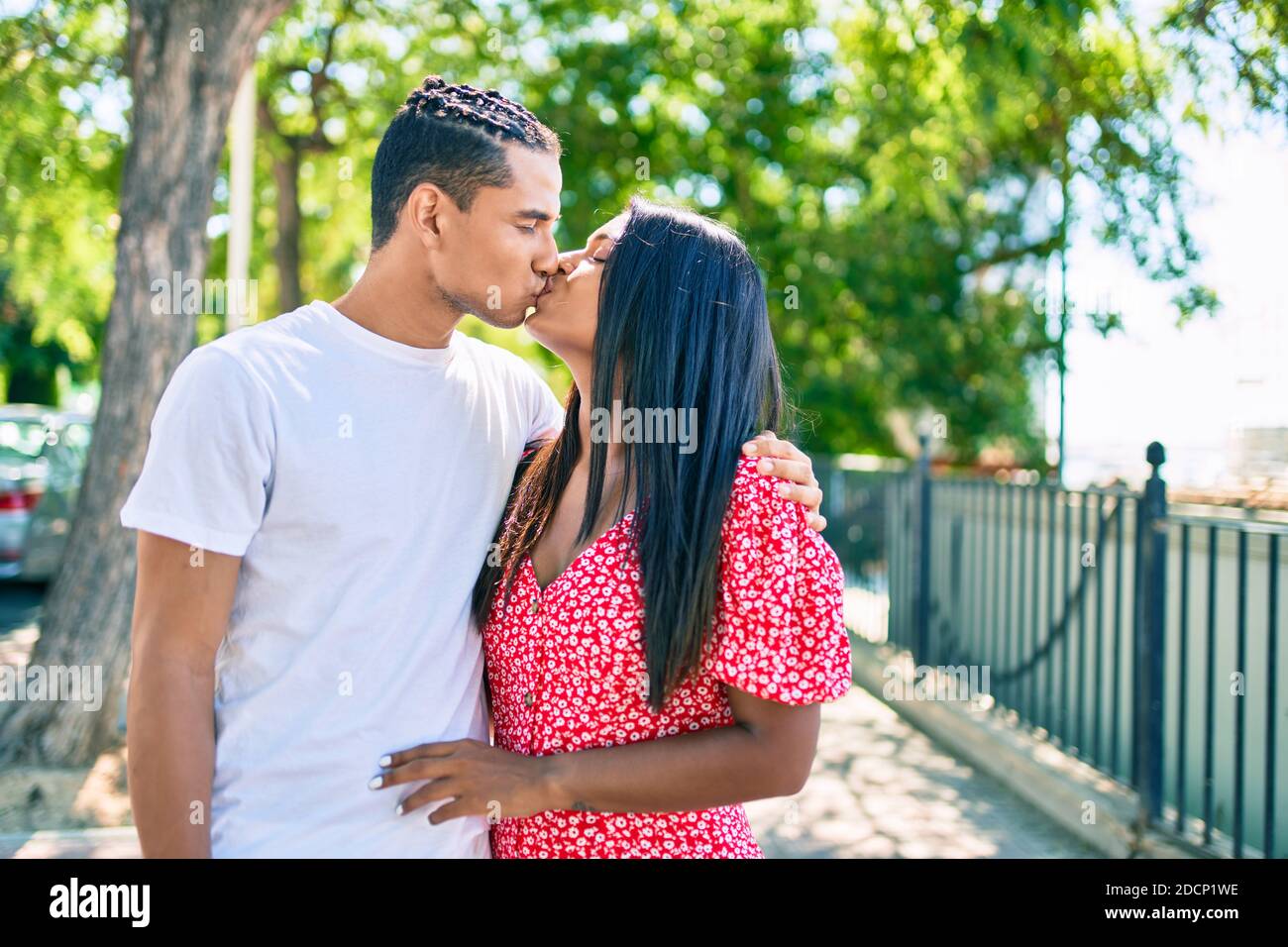 Young latin couple hugging and kissing at the park Stock Photo - Alamy