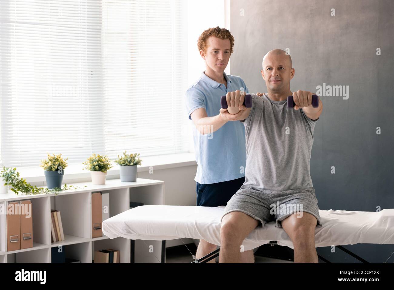 Professional male physiotherapist supporting arm of exercising patient Stock Photo