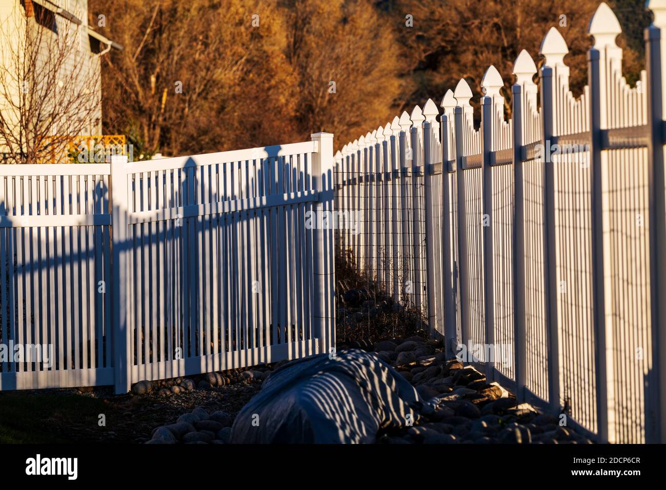 White vinyl picket style fence and shadows; Salida; Colorado; USA Stock Photo