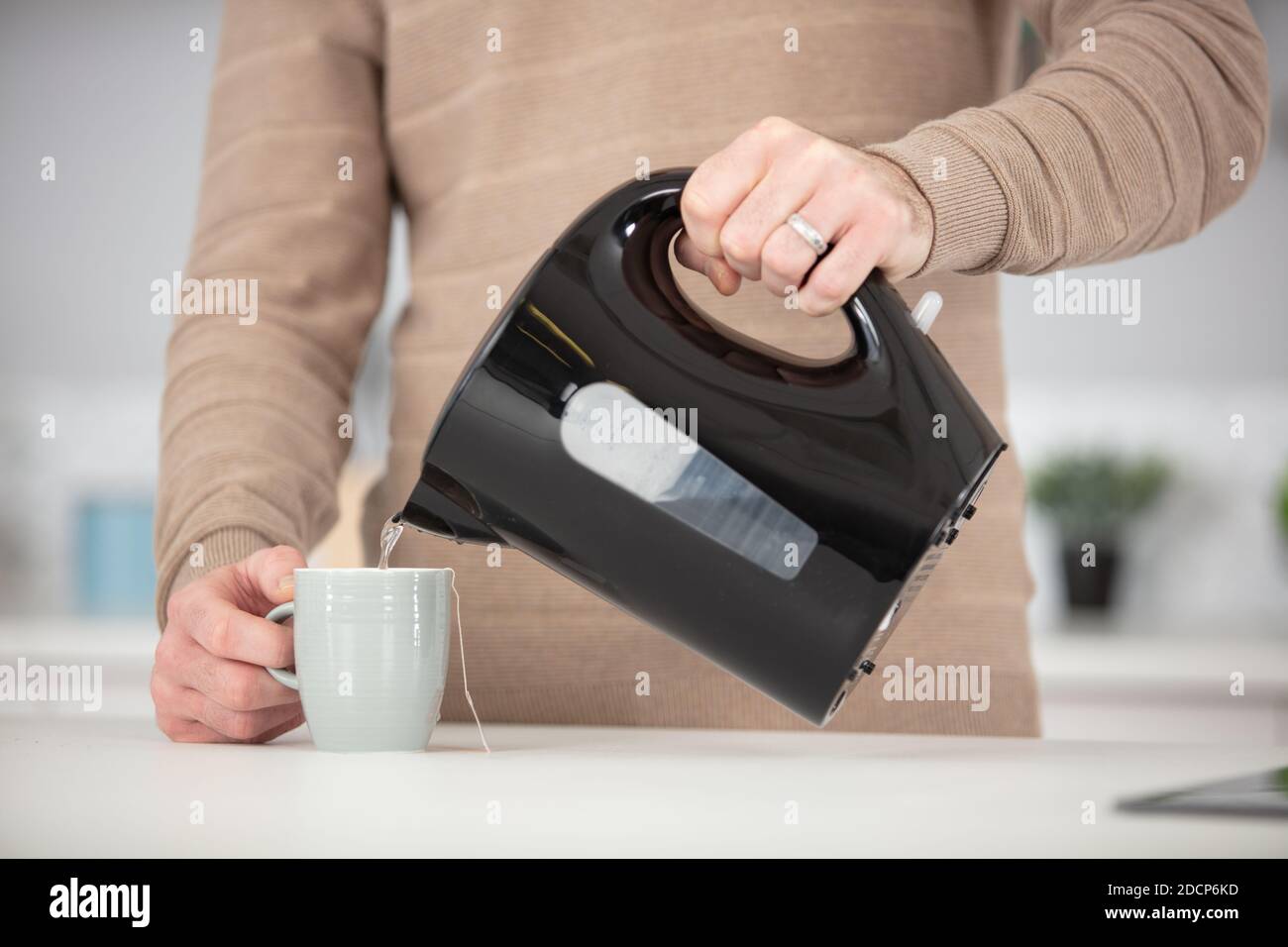 man pouring boiling water from kettle in mug Stock Photo Alamy