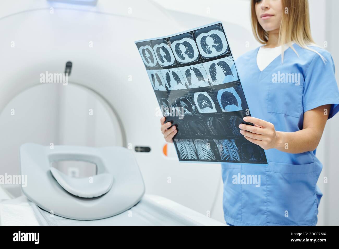 Young female radiologist in blue uniform holding x-ray image of patient head Stock Photo
