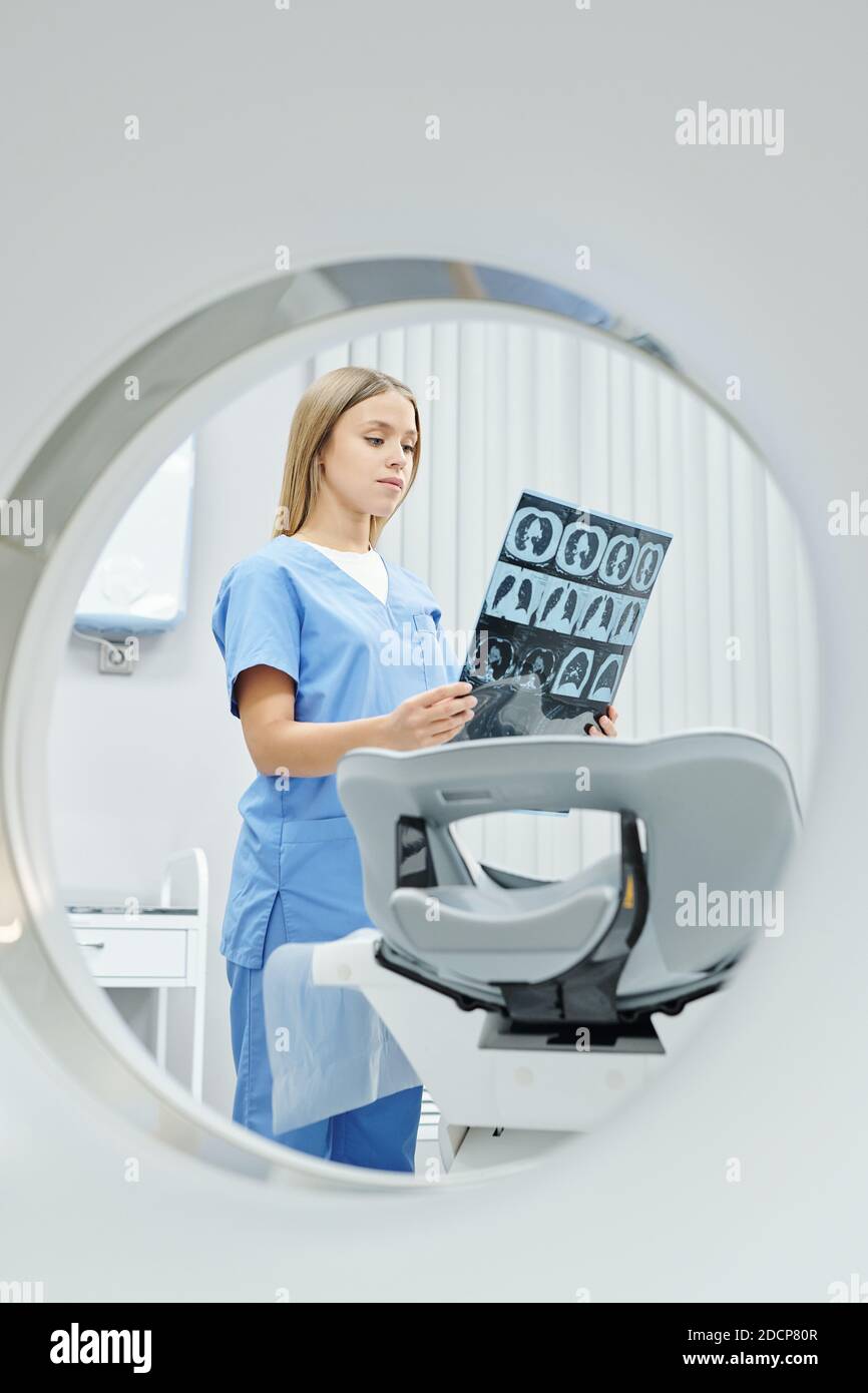 Young radiologist in uniform looking at xray image of patient head and