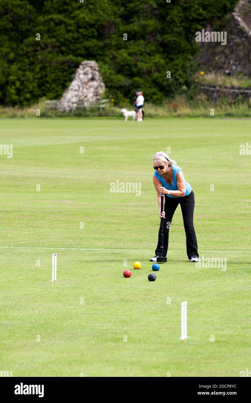Bamburgh, Northumberland, England - July 16th 2020:Mature lady playing croquet in a rural setting in Northumbria, England Stock Photo