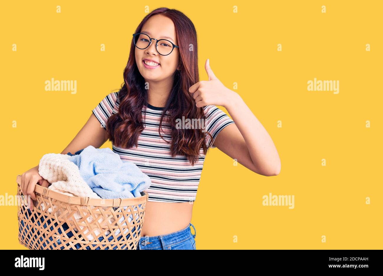 Young beautiful chinese girl holding laundry basket smiling happy and ...