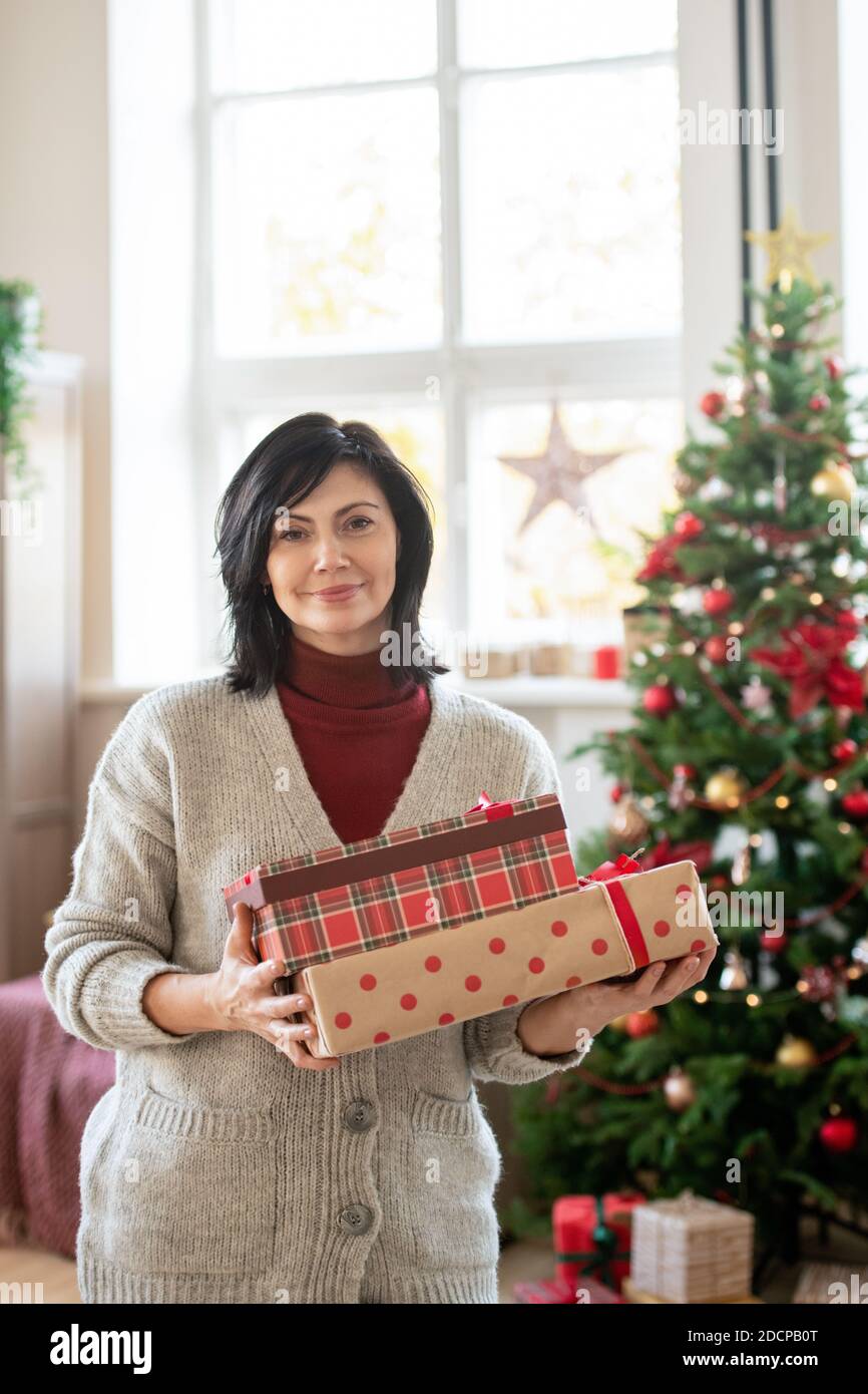 Happy mature brunette woman in casualwear holding giftboxes with presents Stock Photo