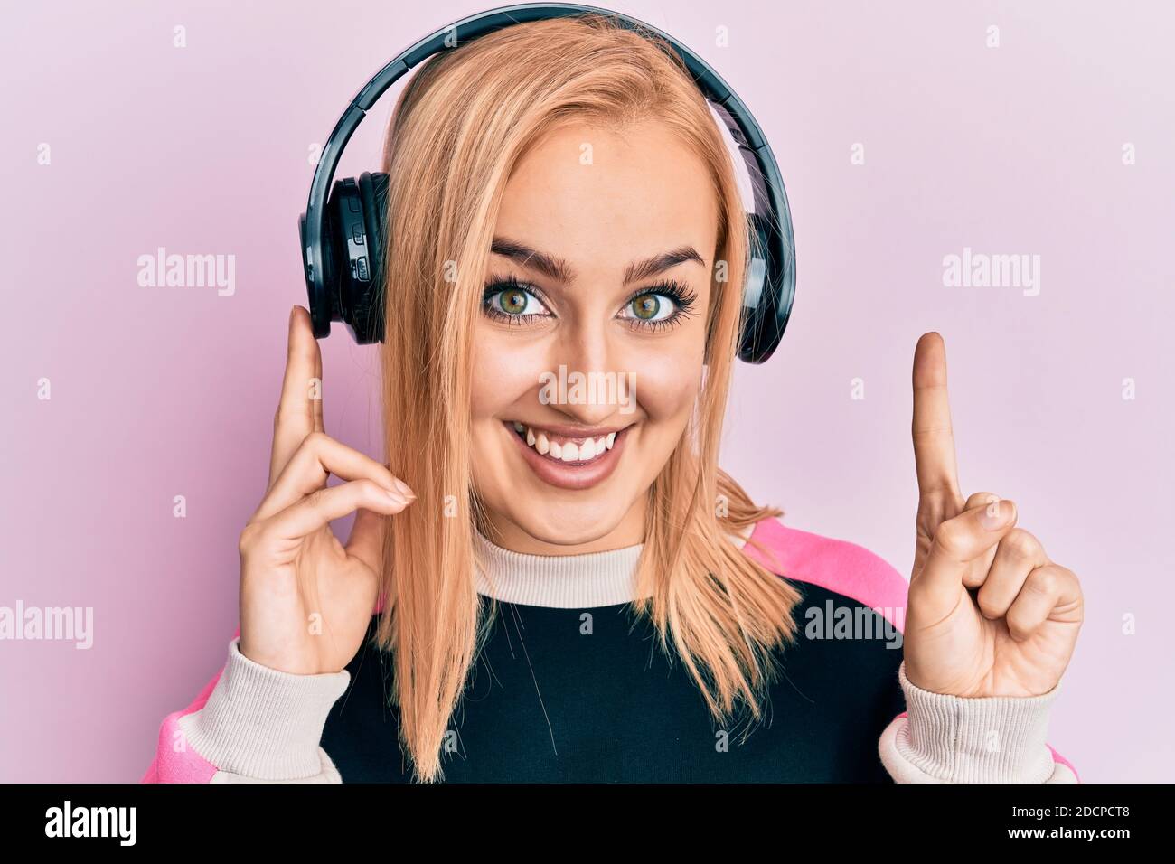 Beautiful caucasian woman listening to music using headphones smiling ...