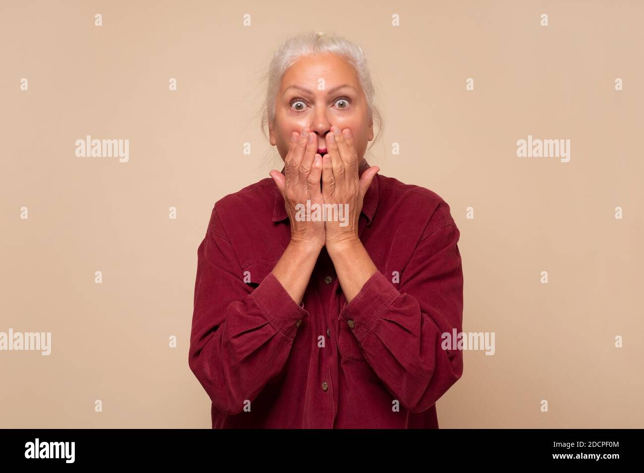 Senior woman being embarrassed, giggling covering mouth with hands Stock Photo