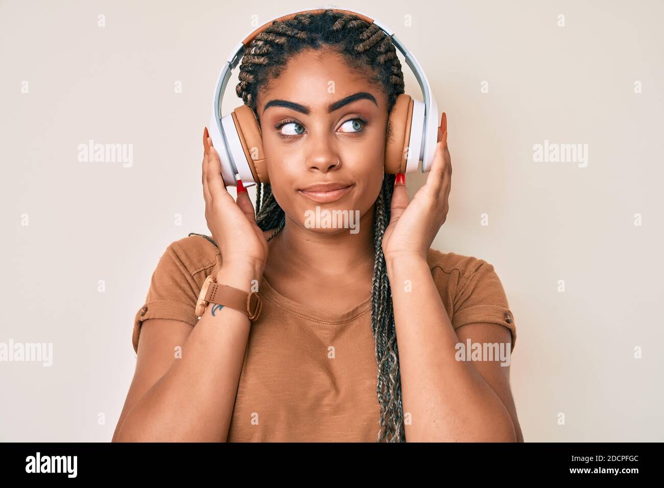 Young african american woman with braids listening to music using ...