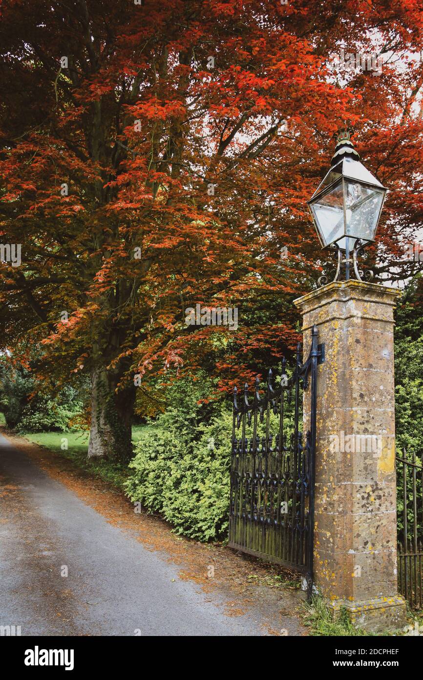 An open iron gate entry to a manor home's driveway entrance with a