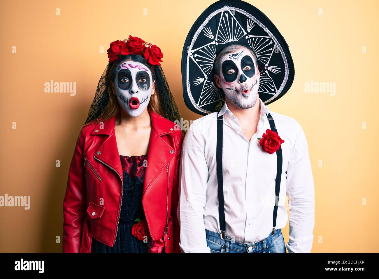 Couple wearing day of the dead costume over yellow afraid and shocked with surprise expression