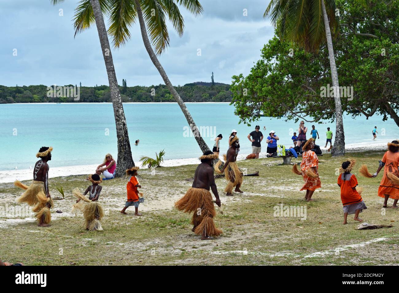 Local Melanesian residents and children perform native Kanak dances to cruise ship visitors in Kuto Bay, Isle of Pines, New Caledonia. Stock Photo