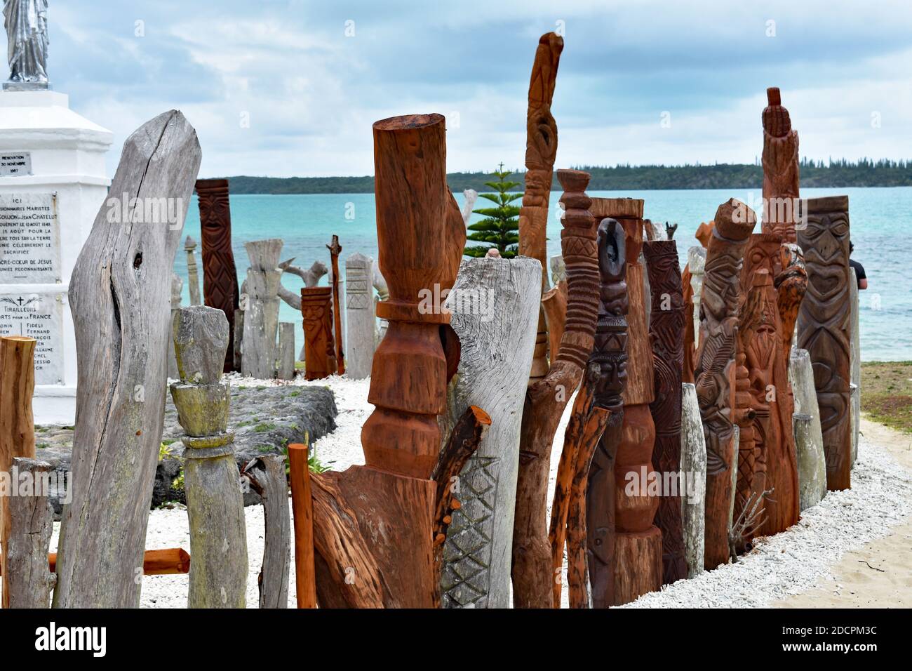 A sculpture of Saint-Maurice is surrounded by a fence made of carved wooden totems in the Bay of St Maurice, Vao, Isle of Pines, New Caledonia. Stock Photo