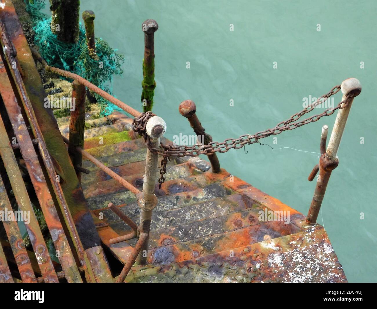 An old disused and derelict set of iron steps leads down to the sea. Now rather dangerous the rusting of the metal has provided some beautiful colours Stock Photo