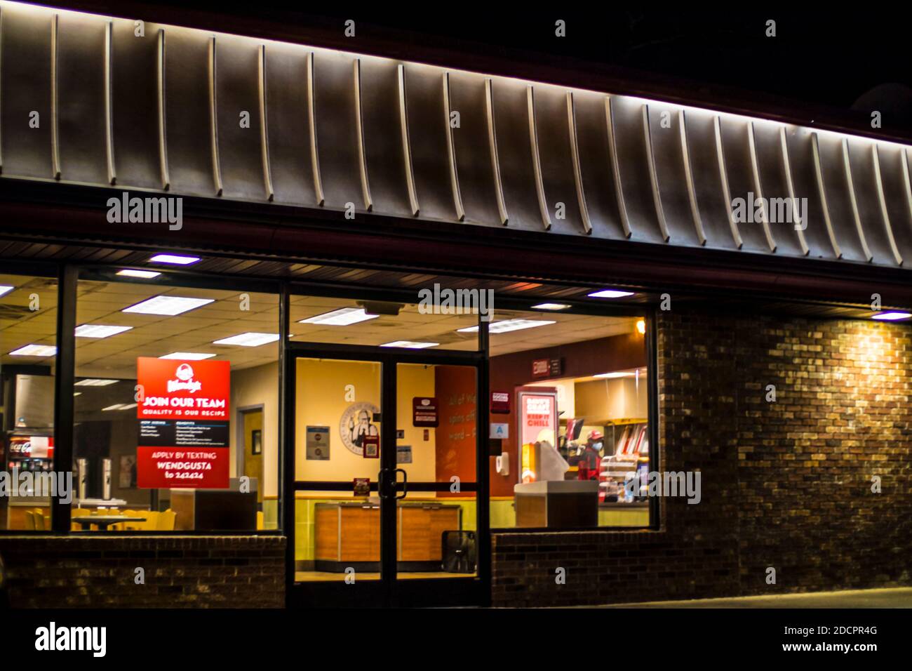 Augusta, Ga / USA - 11 20 20: Wendys Restaurant worker wears face mask inside outside view at night Stock Photo