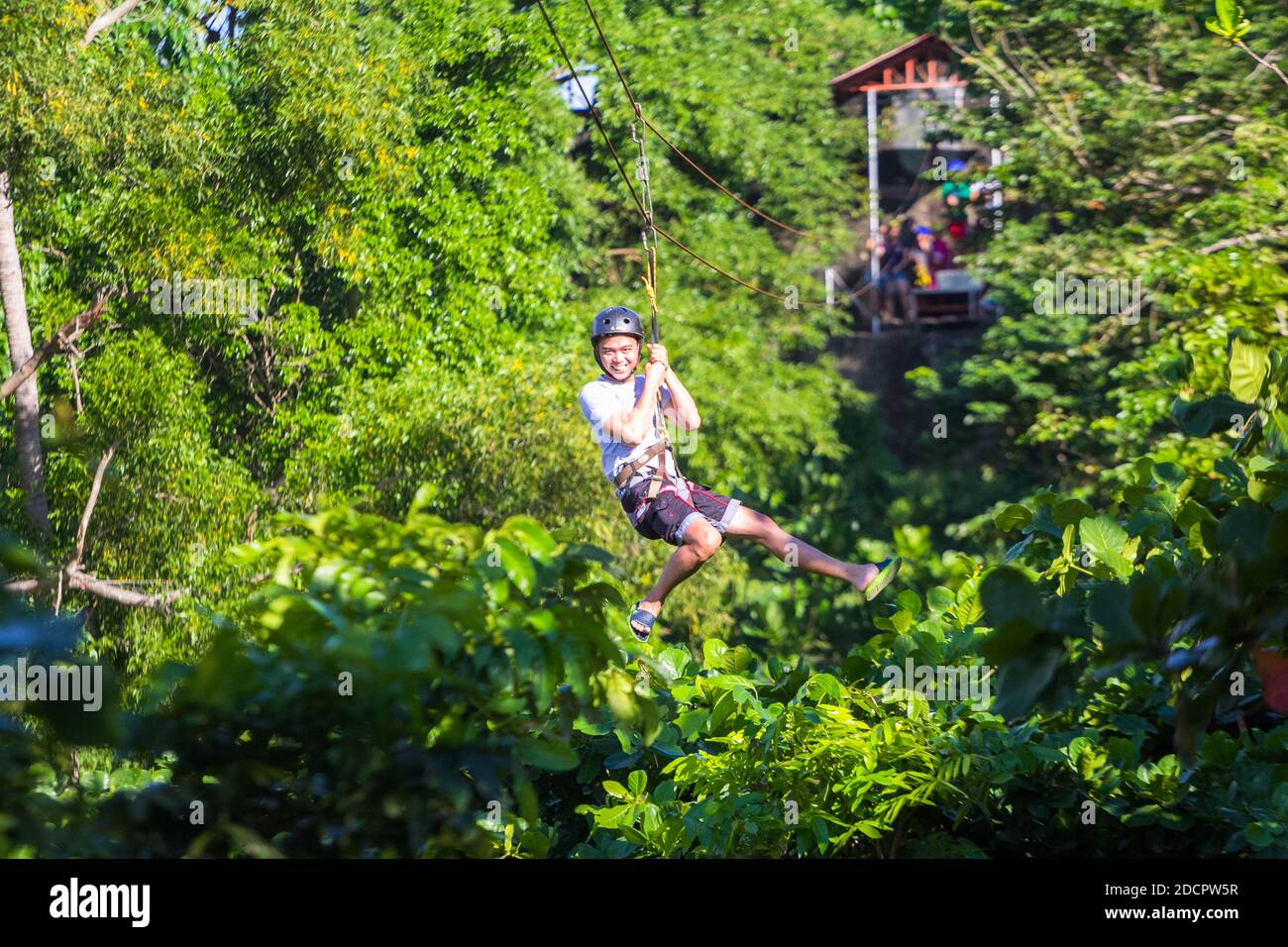 A young Filipino male enjoying a zip line in Corregidor Island, Philippines Stock Photo