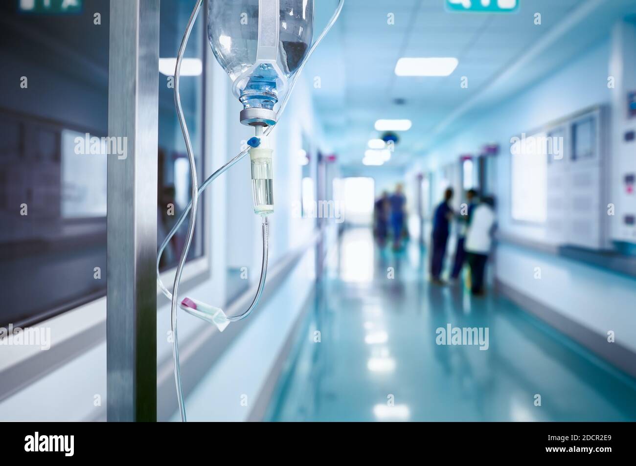 Intravenous drip in the hospital hallway on the background of blurred  staff. Stock Photo