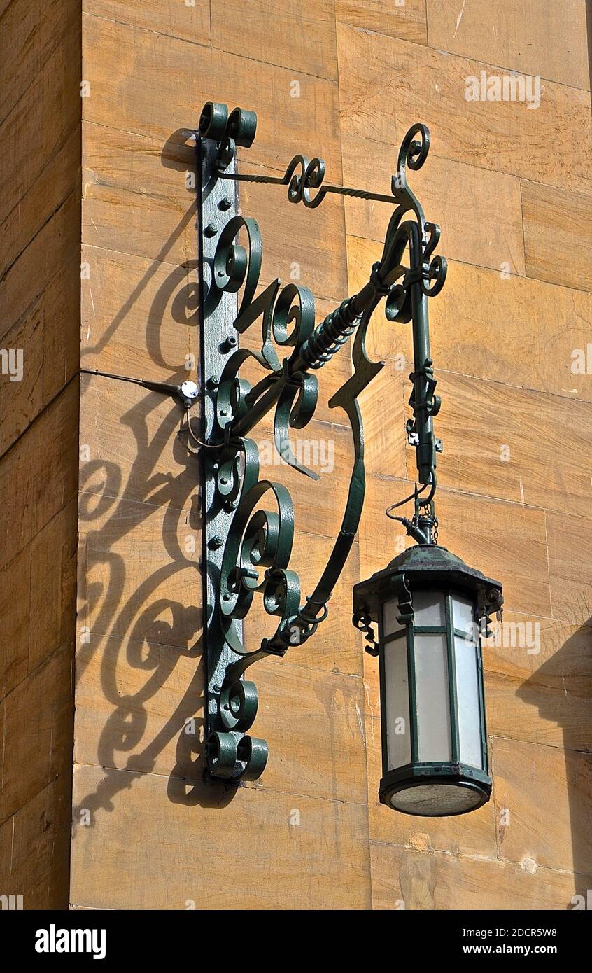 An ornate wrought iron Victorian street light attached to a Sandstone wall. Stock Photo