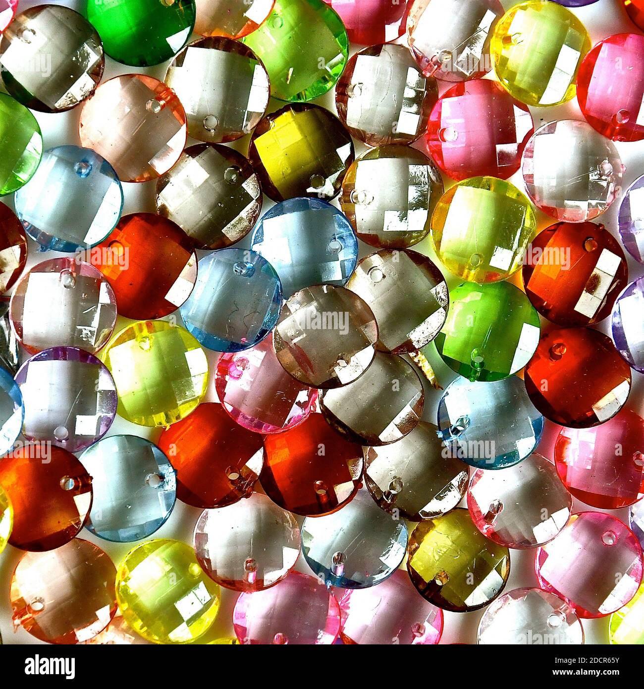 Colourful disc shaped translucent jewels with bevelled facets on the faces. Stock Photo