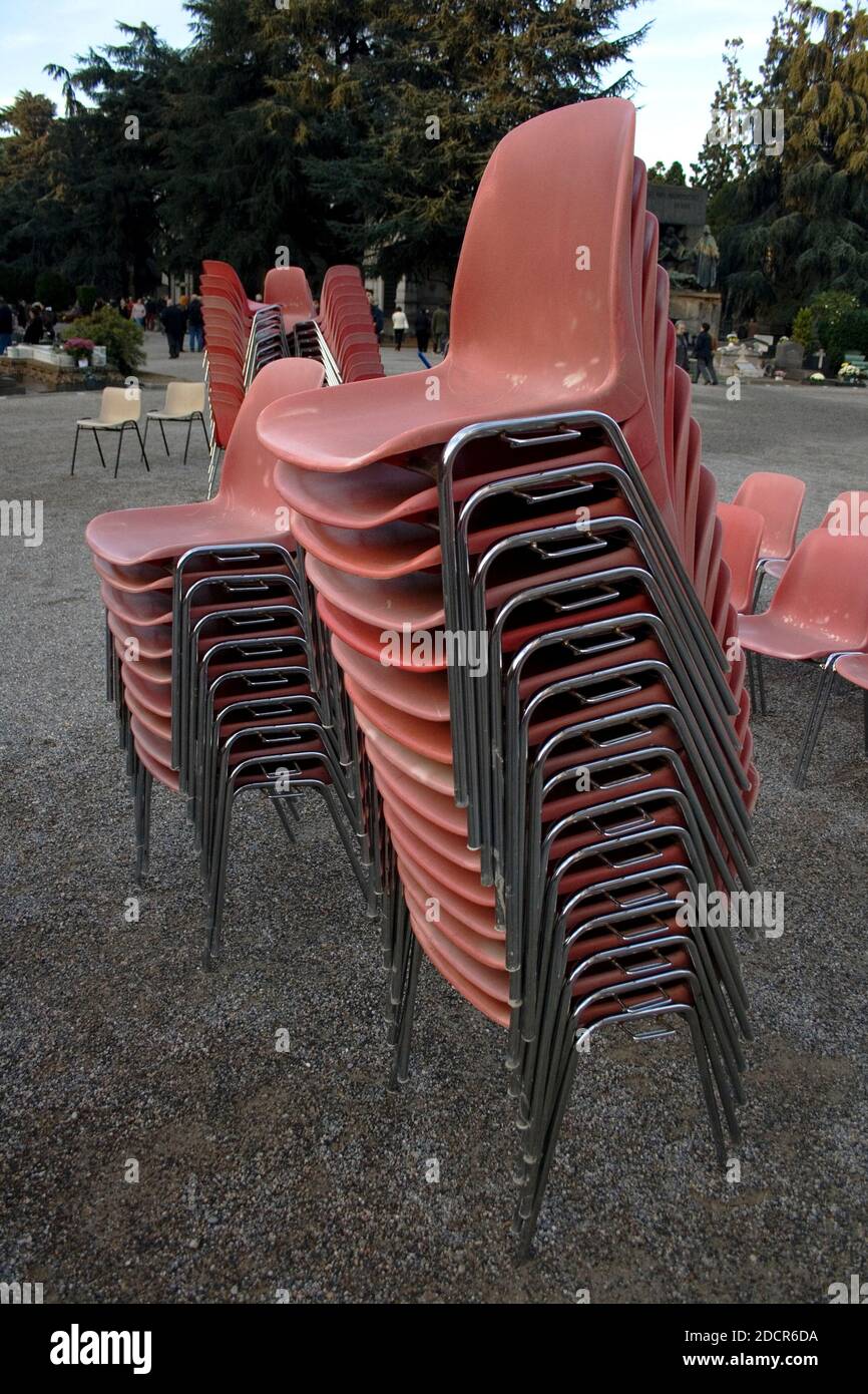 Red palstic and iron chairs are stacked on top of each other in the street Stock Photo Alamy