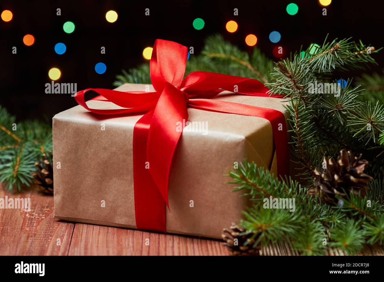 Christmas or New Year gift box with red ribbon on fir branches against ...