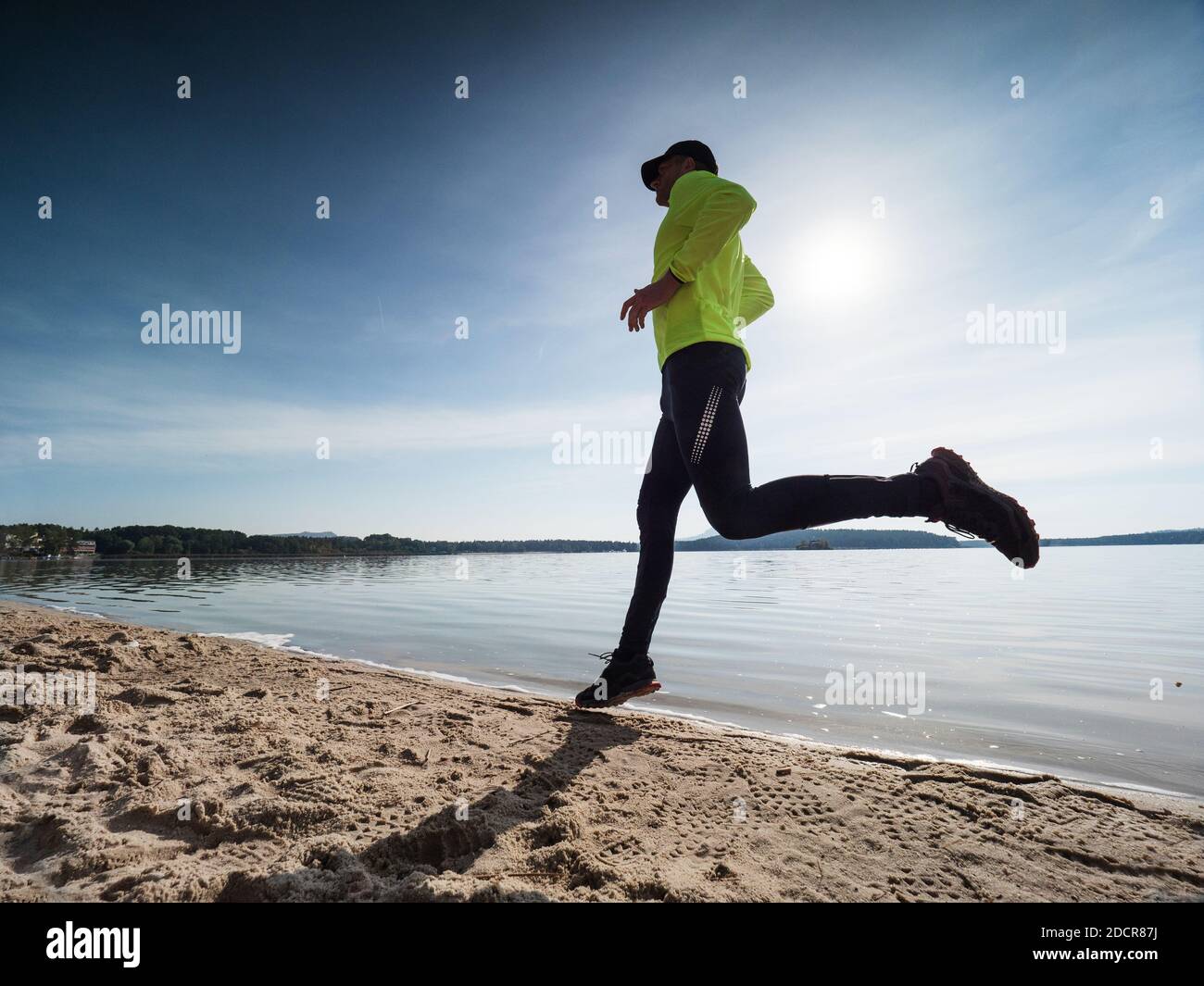 Yellow jersey and black leggings running sportsman run on the sandy beach early morning in summer holiday resort Stock Photo Alamy