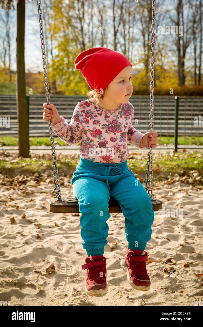 Cute baby girl on a swing in a playground Stock Photo