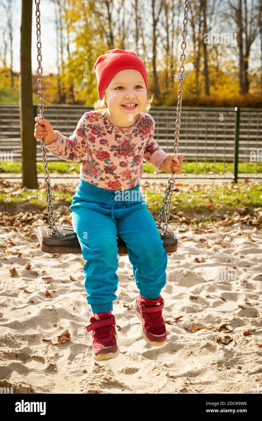 Cute baby girl on a swing in a playground Stock Photo