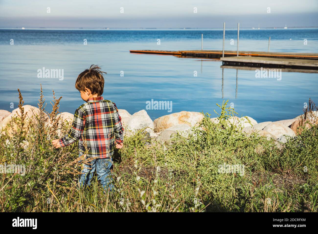 A child, kid or toddler at the seaside bears childhood and discovers the beauty of nature gaining eagerness, learning life and feeding his curiosity Stock Photo
