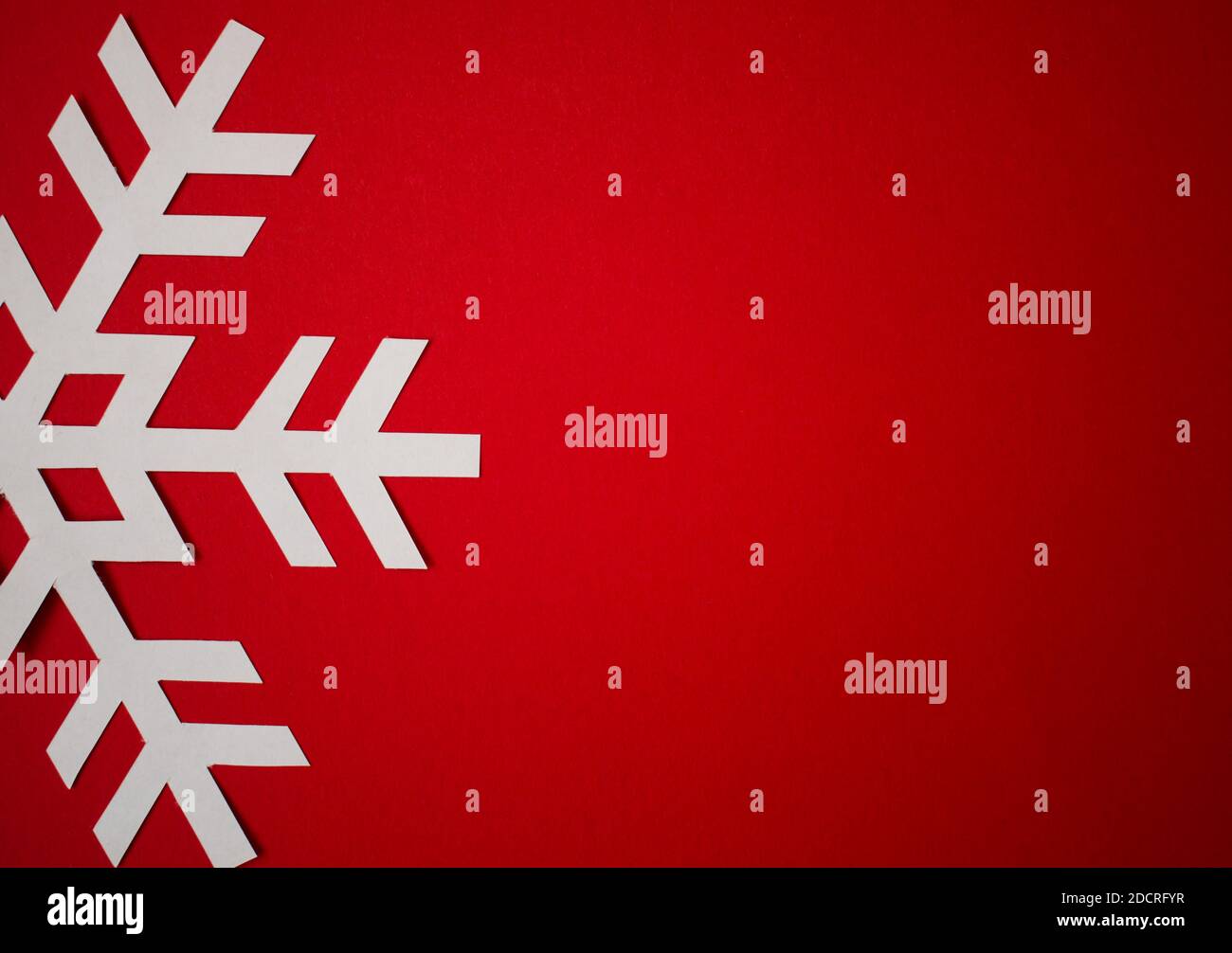 One white cut out paper snowflake on Christmas red background, greeting ...