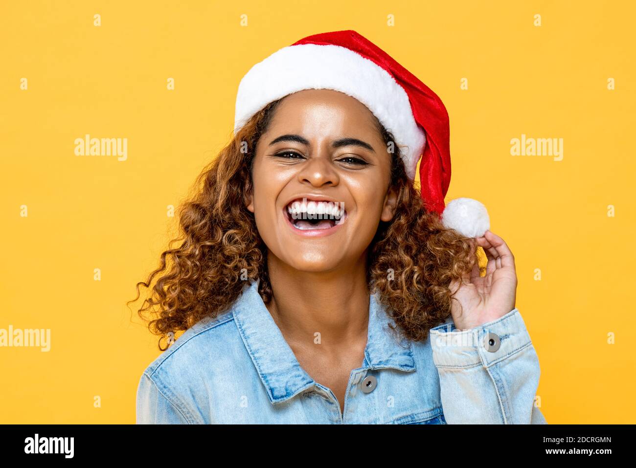 Close up portrait of smiling surprised African American woman wearing Christmas hat on yellow isolated background Stock Photo