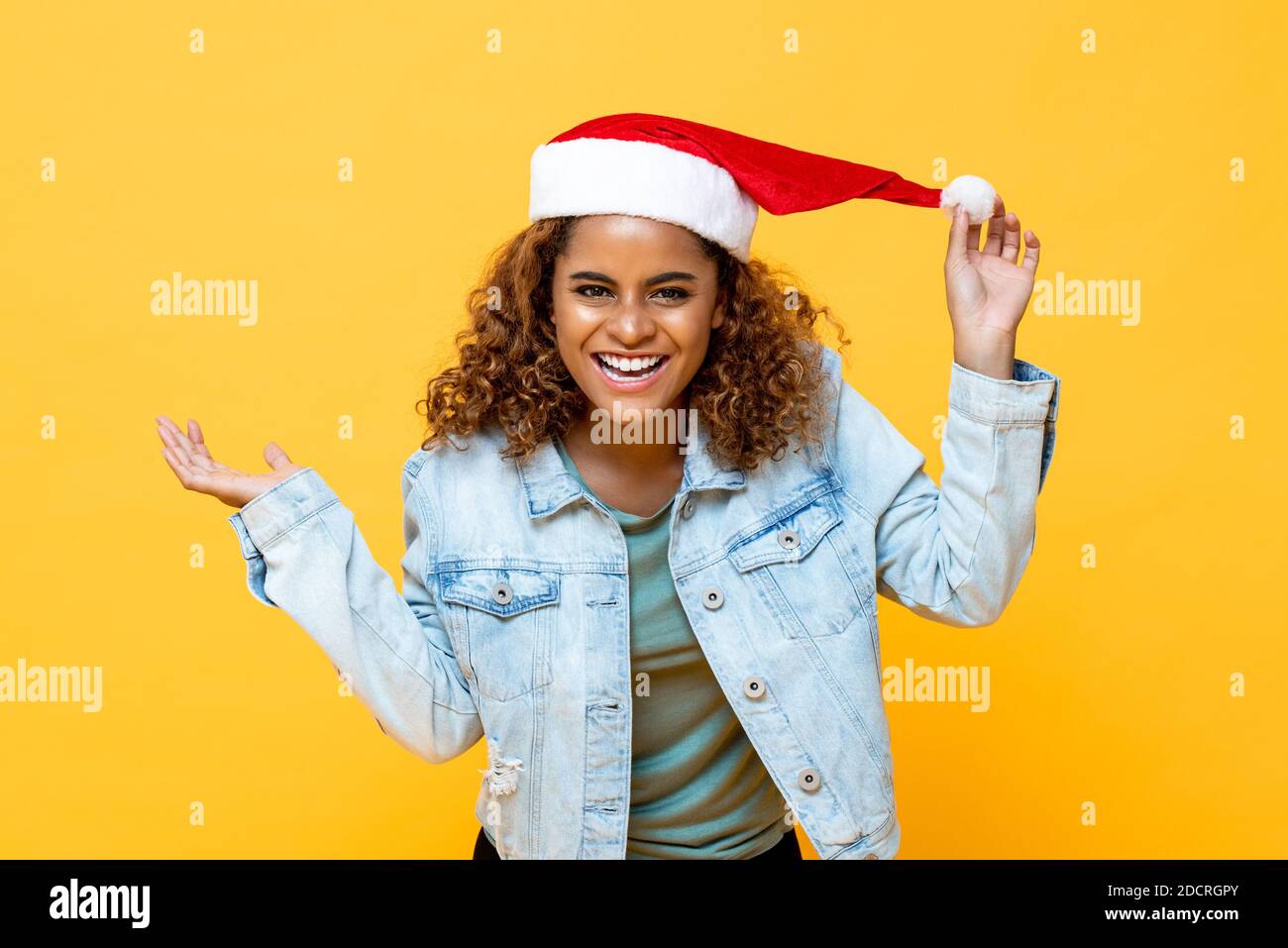 Fun surprised happy African American woman wearing Christmas hat smiling in yellow isolated background Stock Photo
