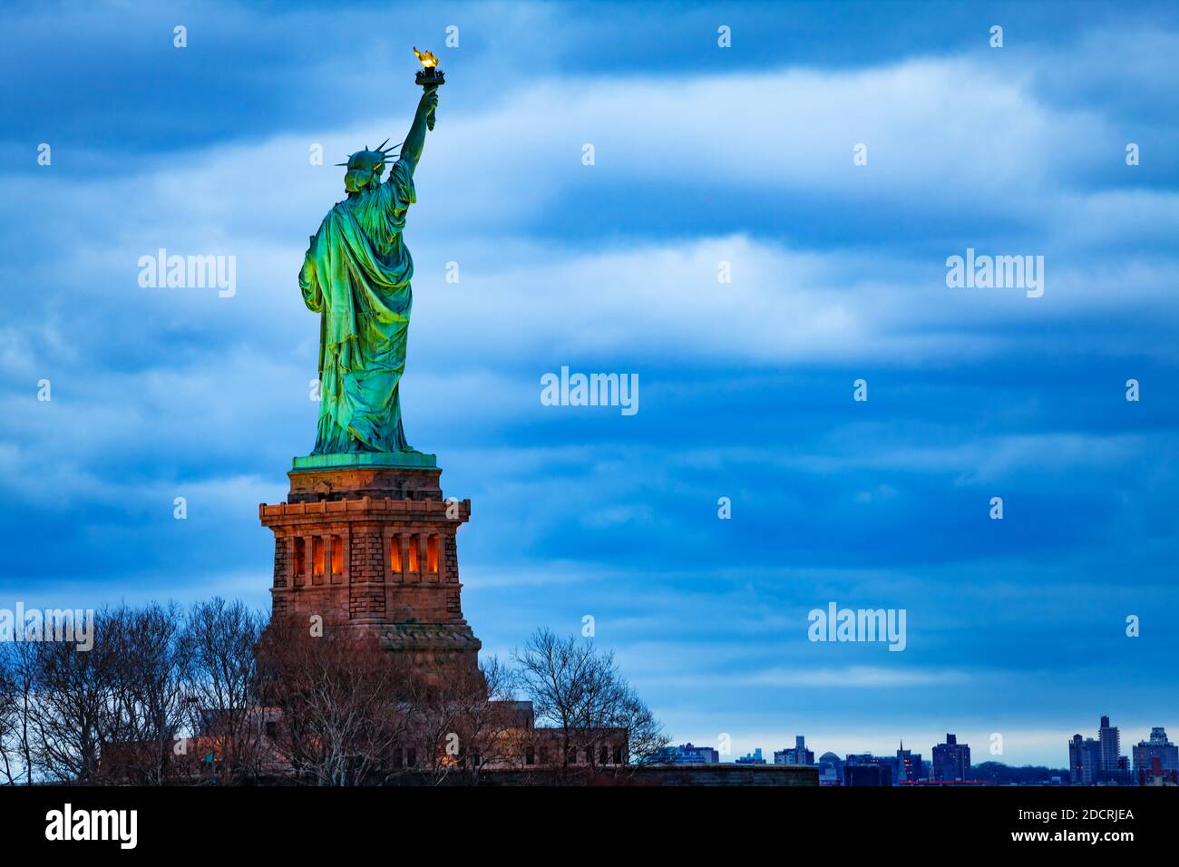 The Statue of Liberty over the New York cityscape from Black Tom Island at evening dusk Stock Photo