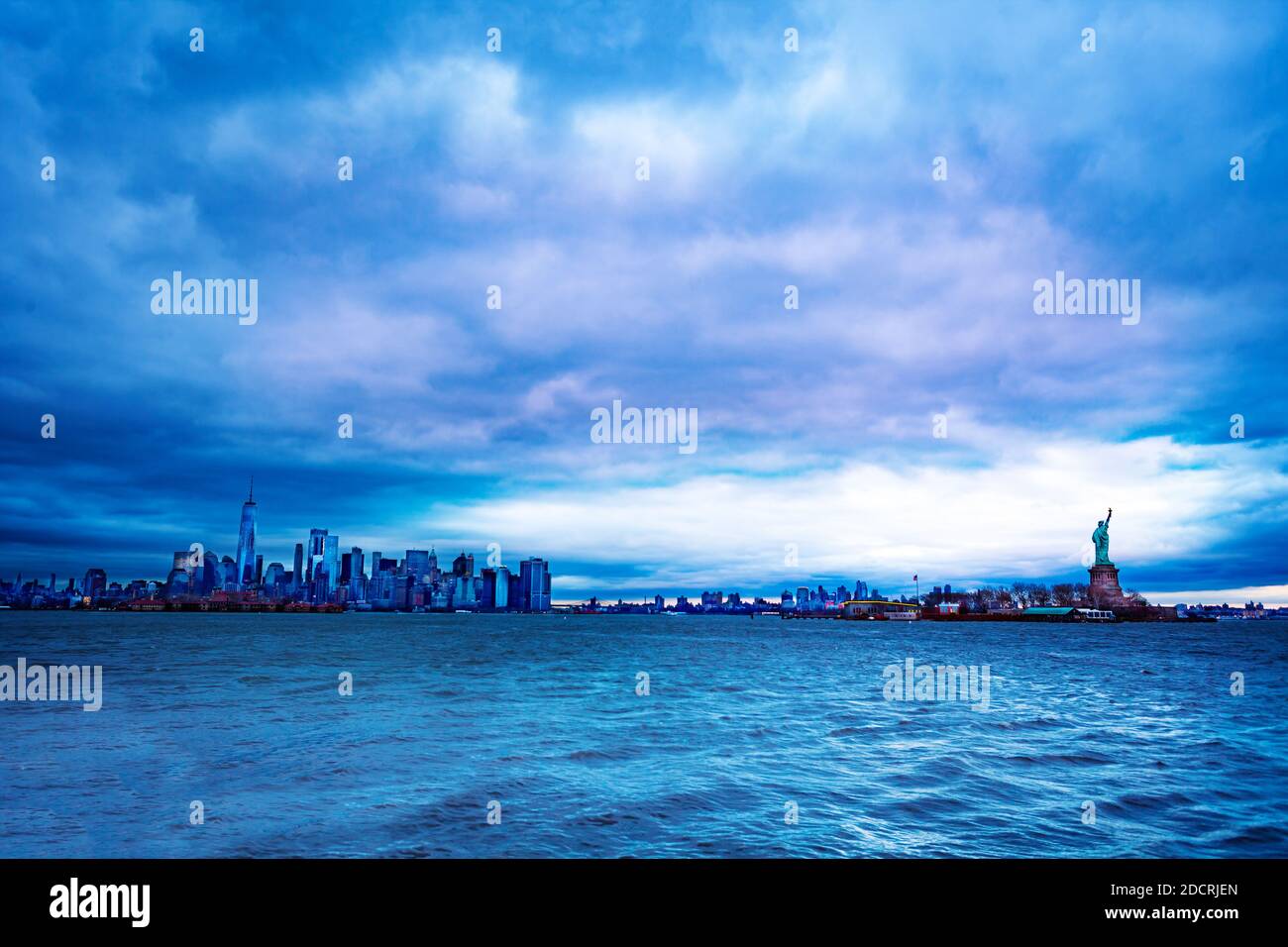 The Statue of Liberty over the New York cityscape at the evening dusk and cloudy weather Stock Photo