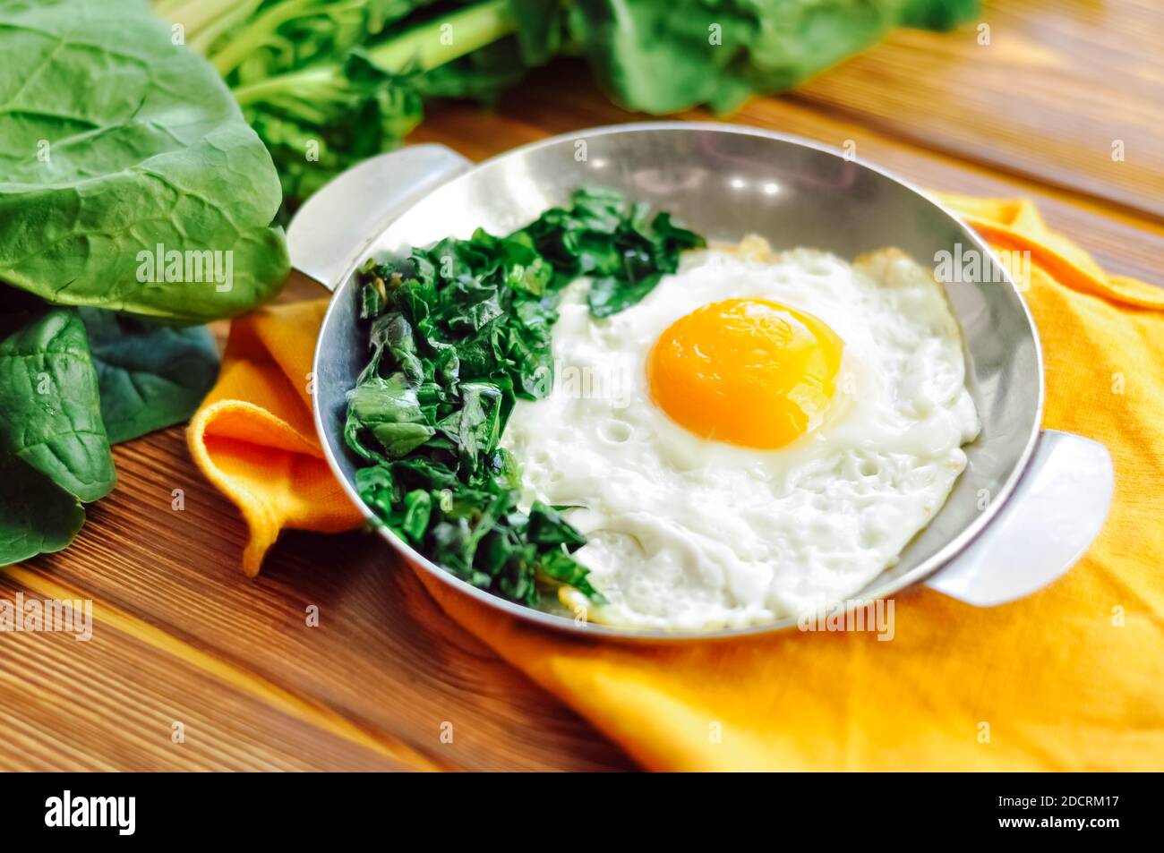 Green cooked spinach with fried egg on iron pan plate. Fried eggs ...