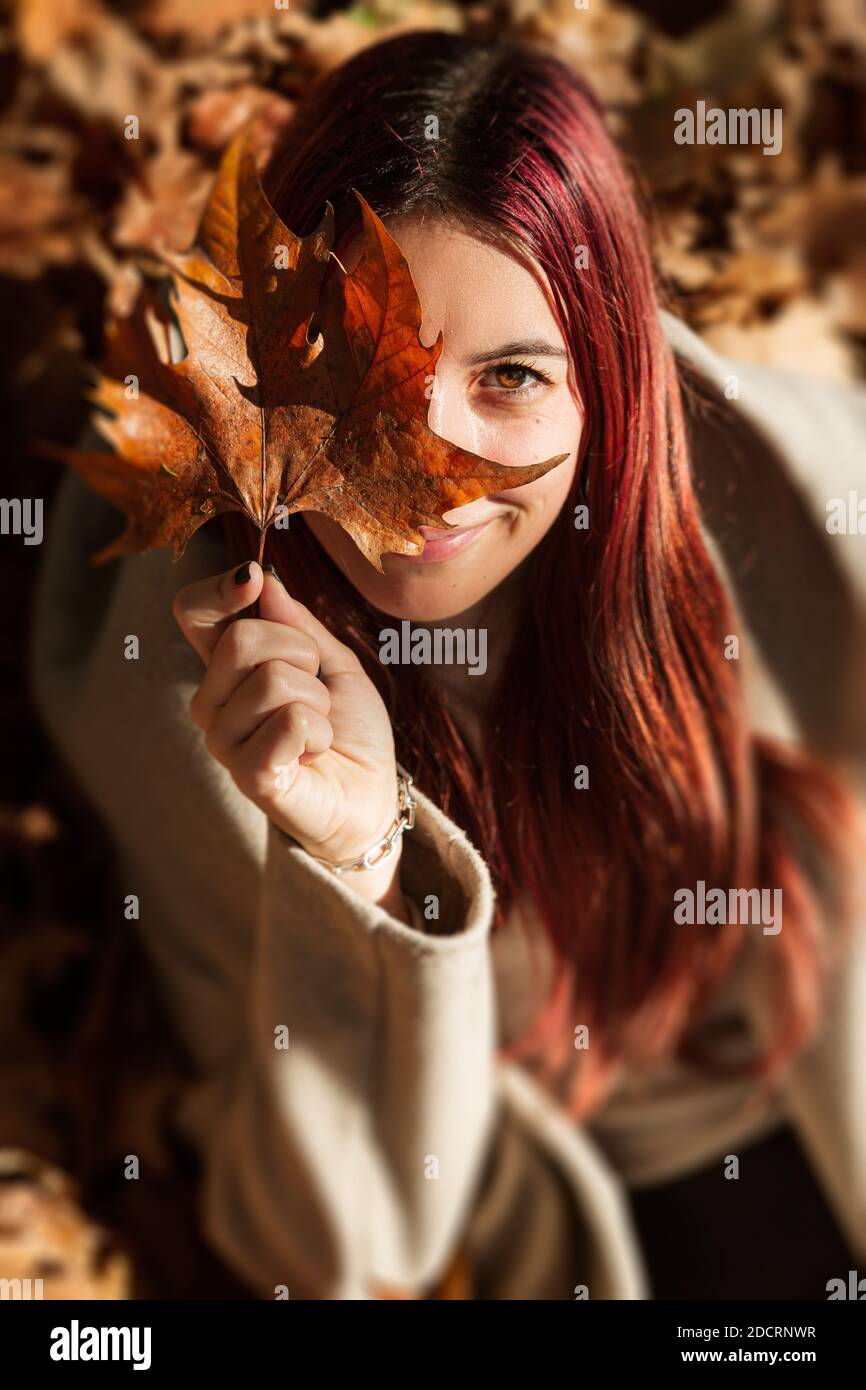 A vertical shot of a beautiful Caucasian girl covering half her face ...