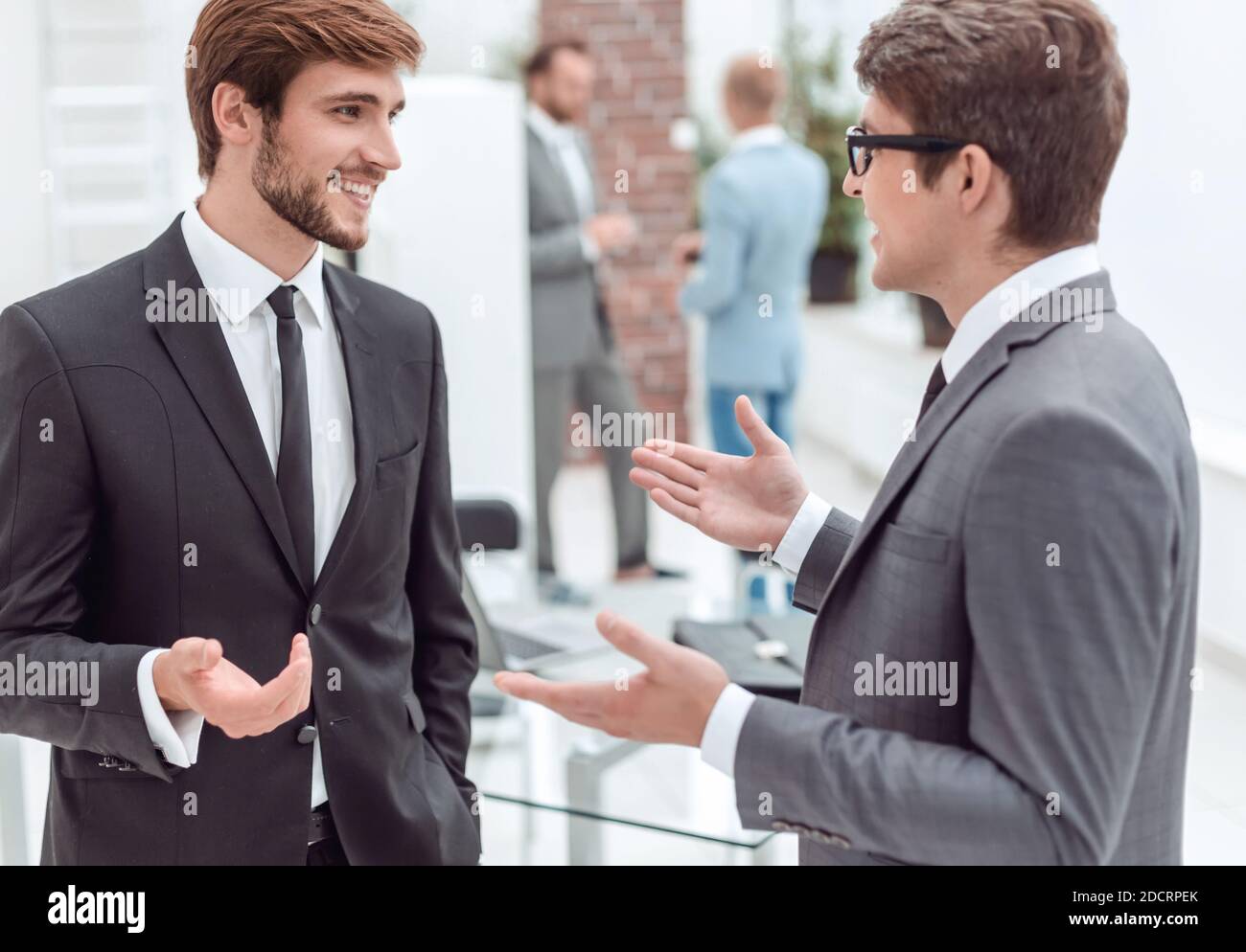 two young entrepreneurs talking standing in the office Stock Photo - Alamy