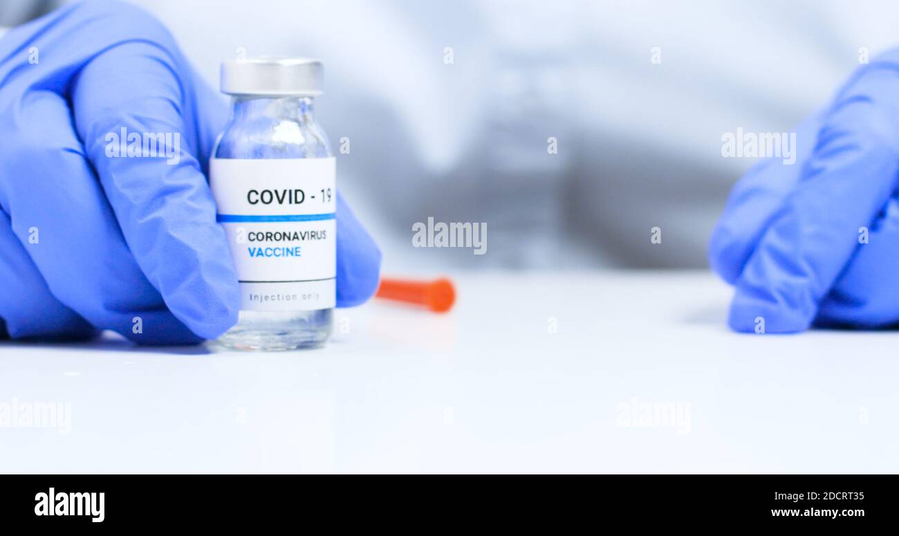 Corona virus Vaccine concept. Close-up of doctor hands in blue medical gloves holding a syringe with liquid vaccines for children or older adults Stock Photo