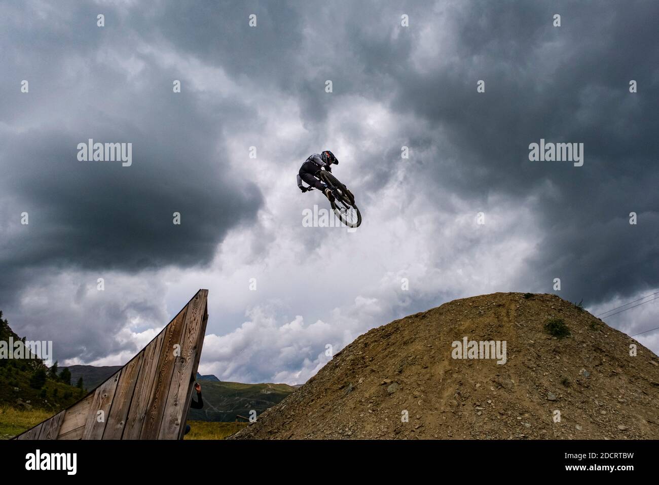 A downhill cyclist is jumping in the Mottolino Bike Park, surrounding  mountains of Livigno in the distance Stock Photo - Alamy