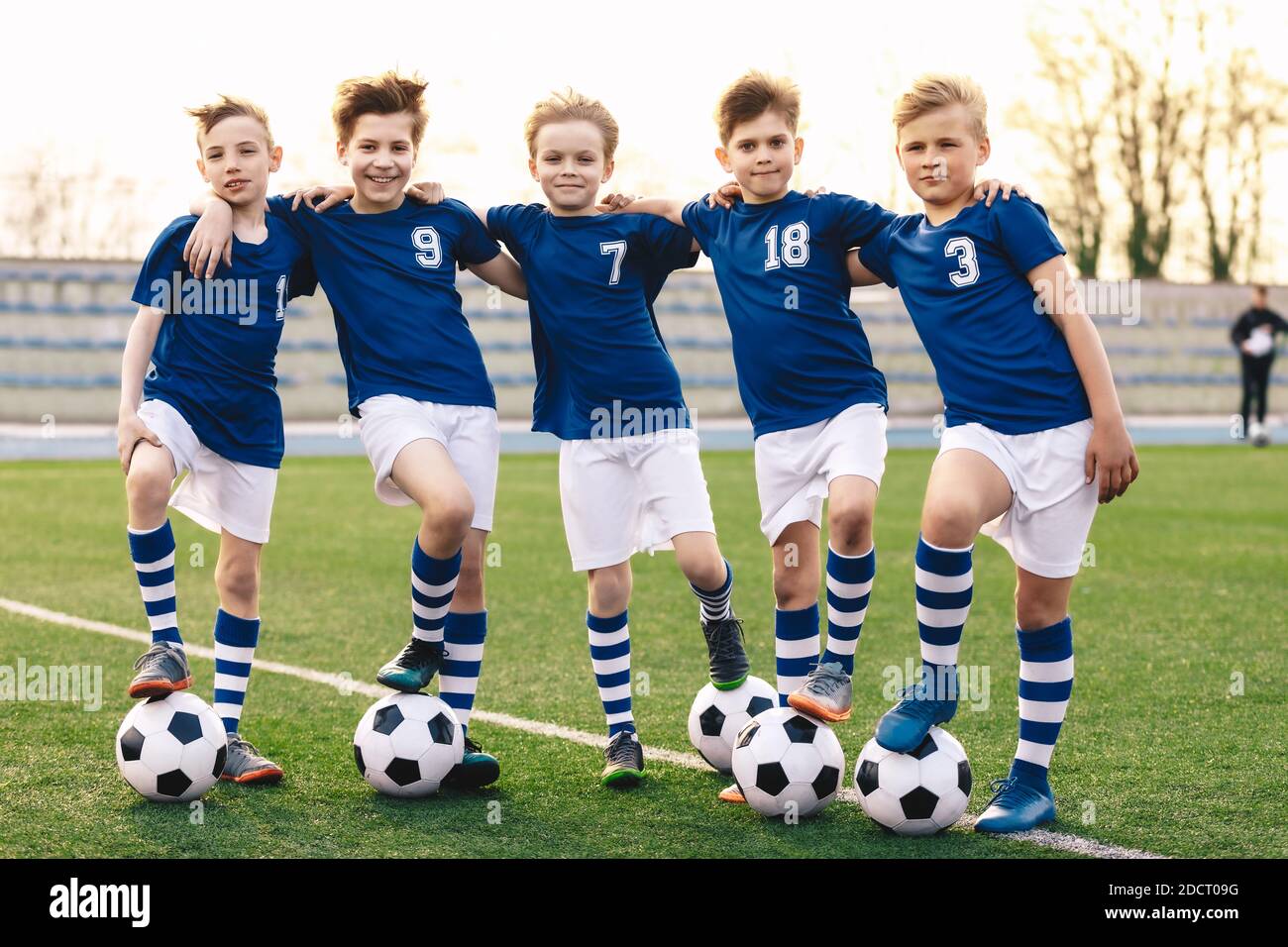 Sporty School Boys in Soccer Team. Group of Children in Football Jersey Sportswear Standing with Balls on Grass Pitch. Happy Smiling Kids in Sport Tea Stock Photo