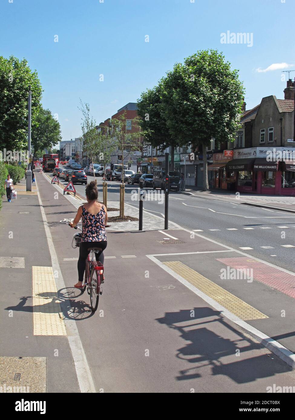 A female cyclist uses the new cycle lane on Lea Bridge Road, London, UK. Part of Waltham Forest's Mini Holland scheme for cycling & safer streets Stock Photo