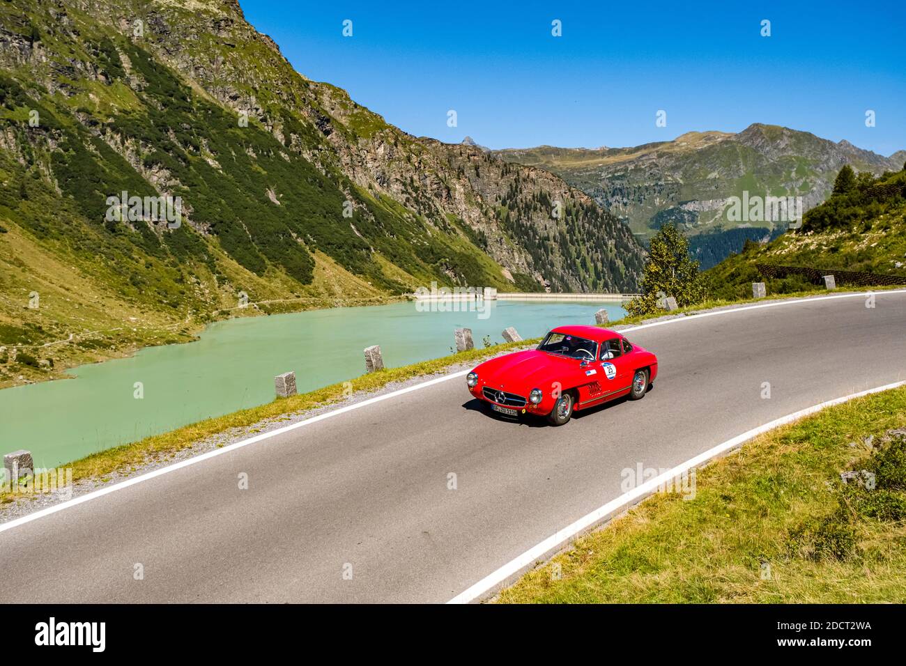 A vintage car Mercedes-Benz 300 SL driving past a lake on Silvretta Hochalpenstrasse during the Arlberg Classic Car Rally. Stock Photo