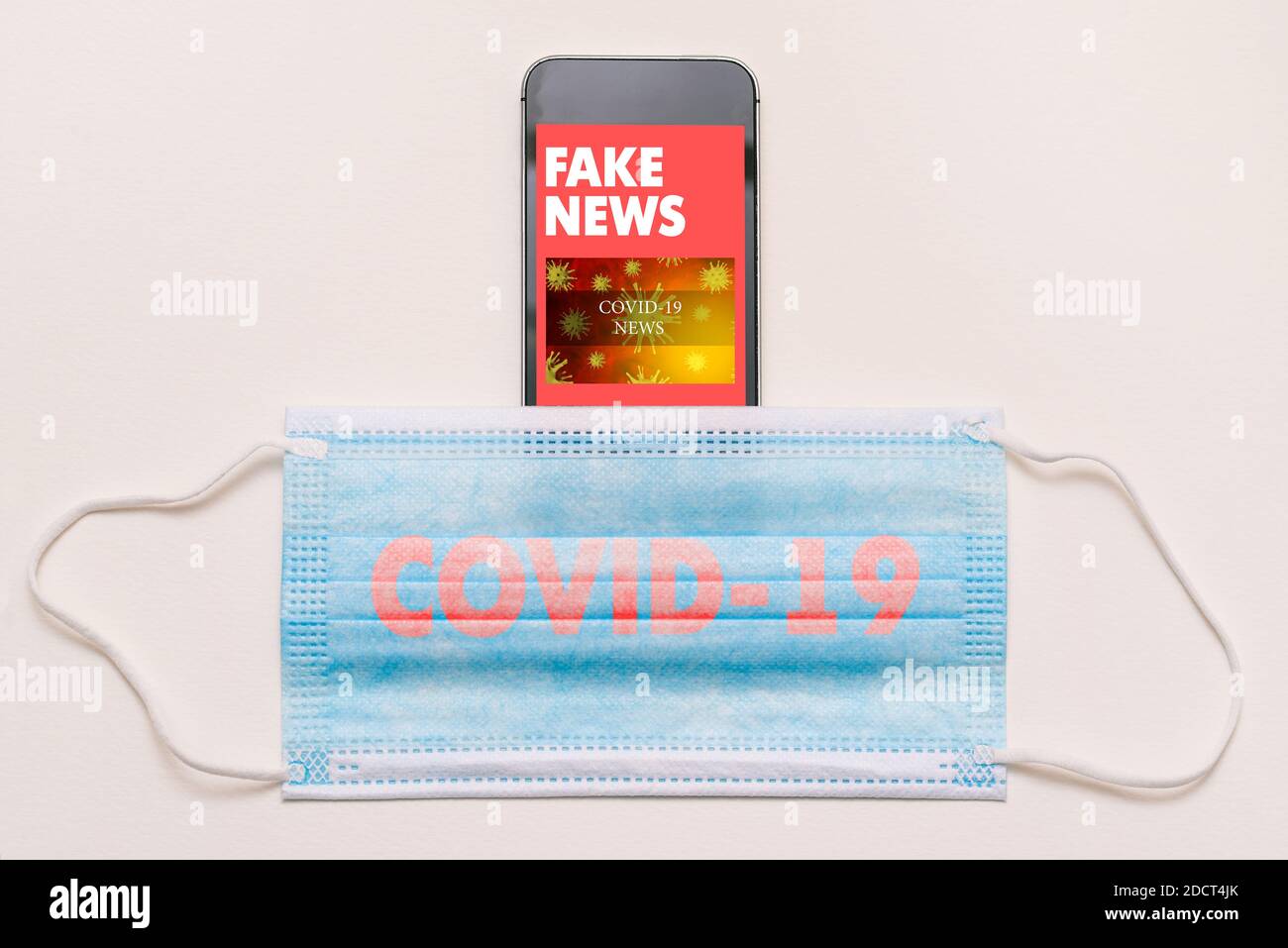 Fake news concept on coronavirus theme. Mobile phone and medical mask with COVID-19 text. News feed on smartphone screen with fake articles. Stock Photo