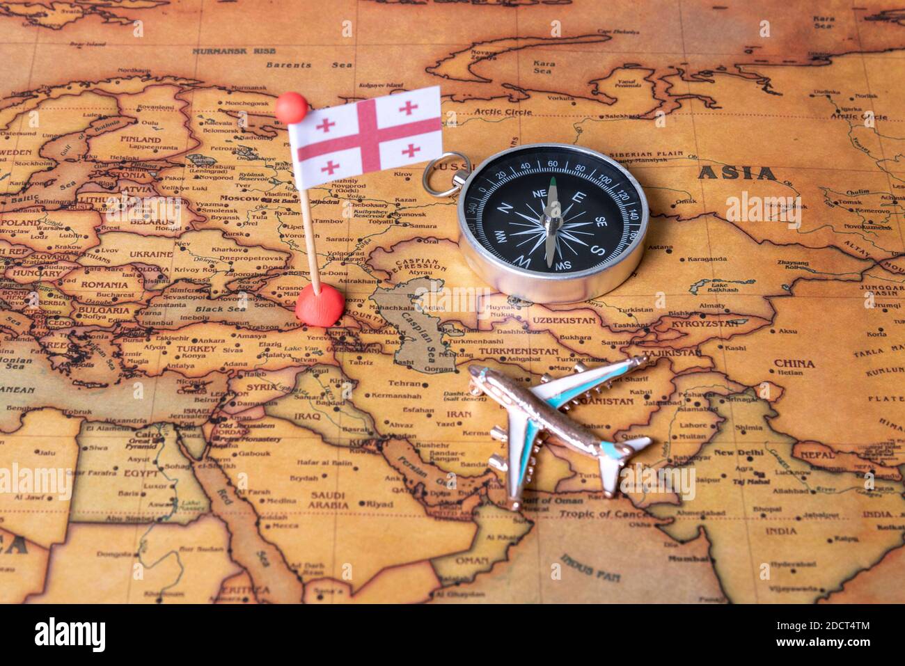 Flag of Georgia, compass and plane on the world map. The concept of travel and tourism. Stock Photo