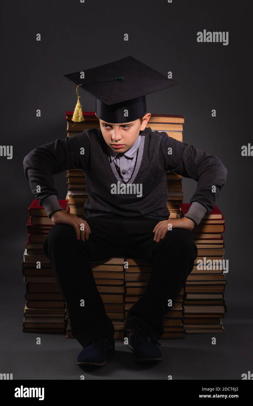 Boy as an angry professor sitting on a makeshift throne from books Stock Photo