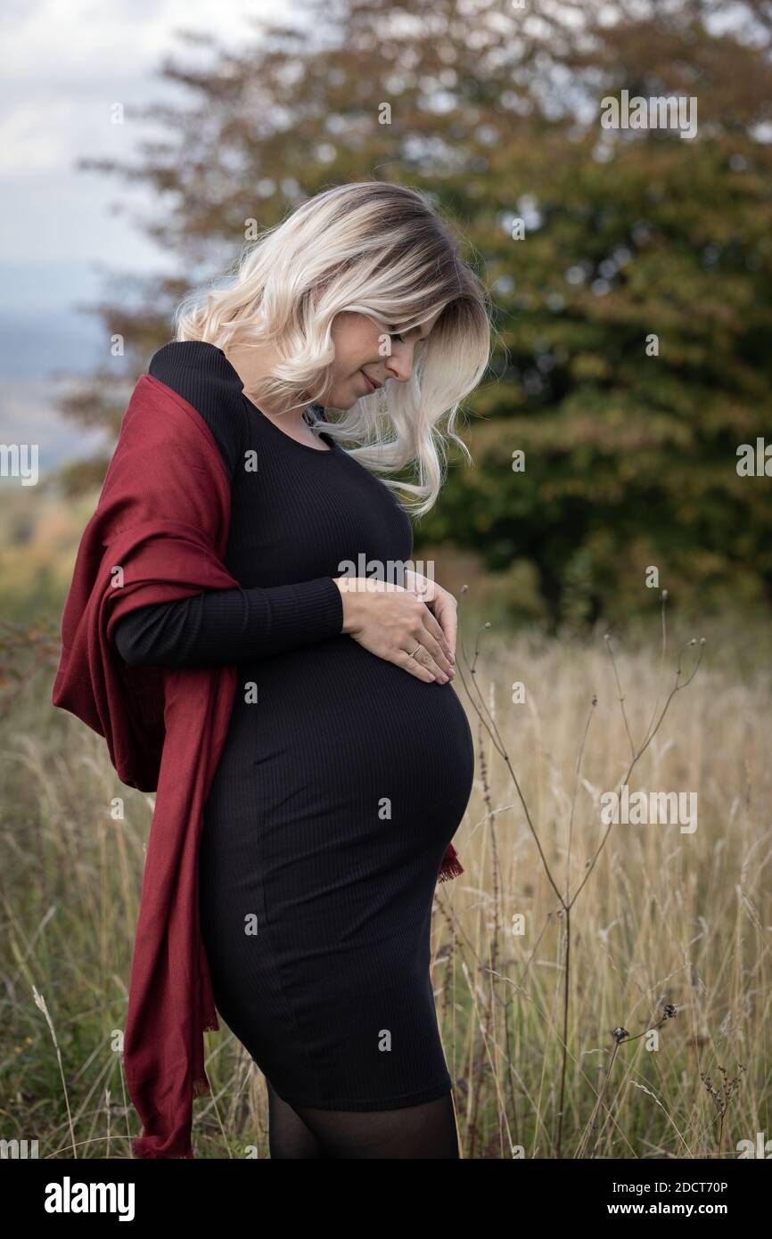 Beautiful pregnant woman with black dress posing outdoor in nature Stock  Photo