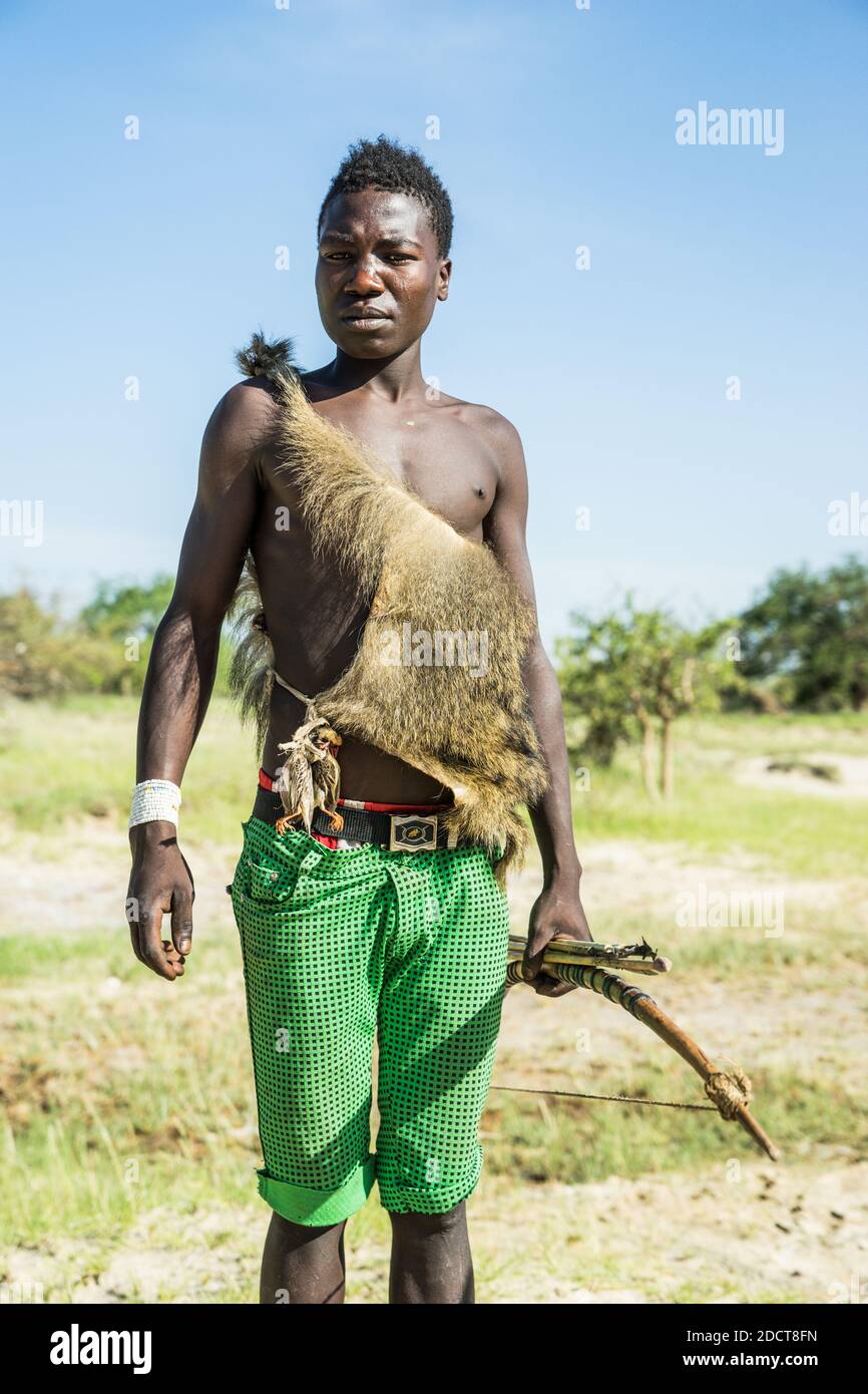 Hadzabe hunter poses with bow and arrow and some small birds attached