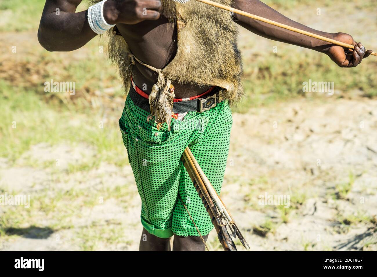 Hadzabe hunter poses with bow and arrow and some small birds attached